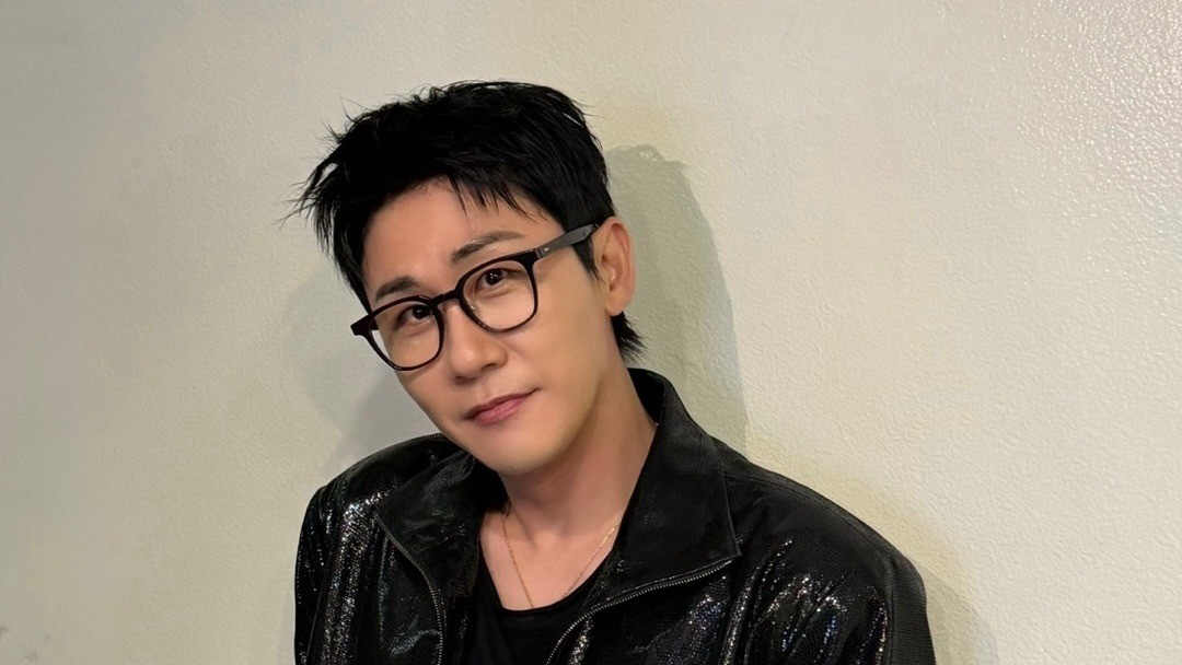 영탁이 벽에 기대어 안경을 쓰고 부드럽게 미소 짓는 모습