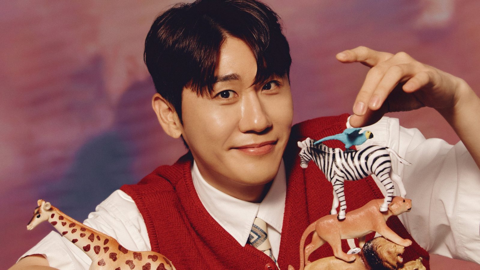 영탁이 붉은색 니트 조끼 차림으로 미니어처 동물 인형을 손에 들고 웃고 있는 모습