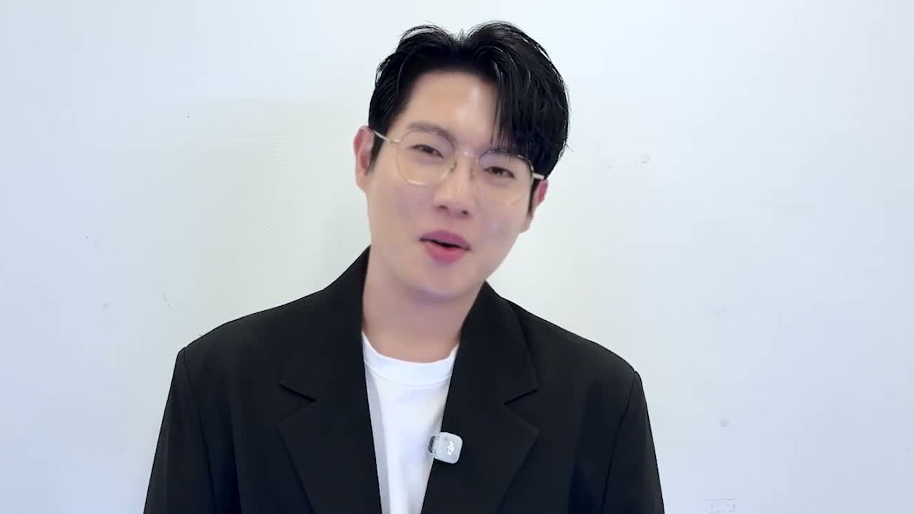 손태진이 안경을 쓰고 검정 재킷 차림으로 환하게 웃으며 말하는 상반신 모습