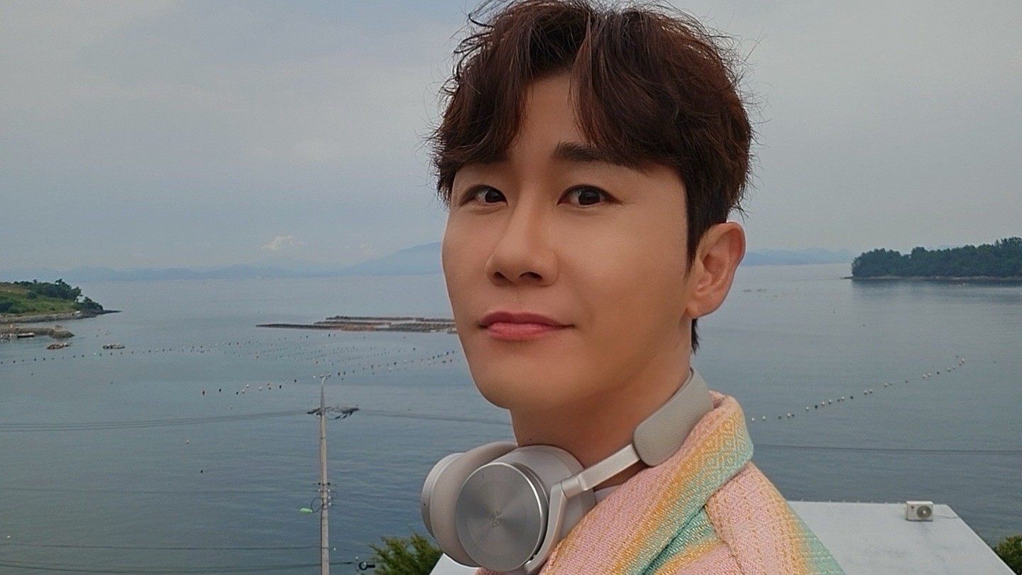 영탁이 목에 헤드폰을 걸고 바닷가를 배경으로 서 있는 모습
