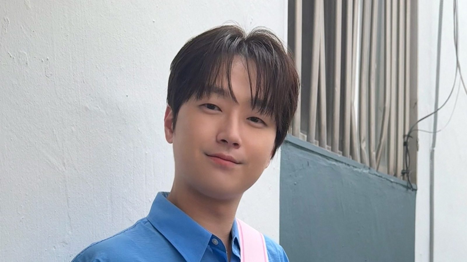 이찬원이 파란 셔츠를 입고 흰 벽 앞에서 미소 짓는 모습