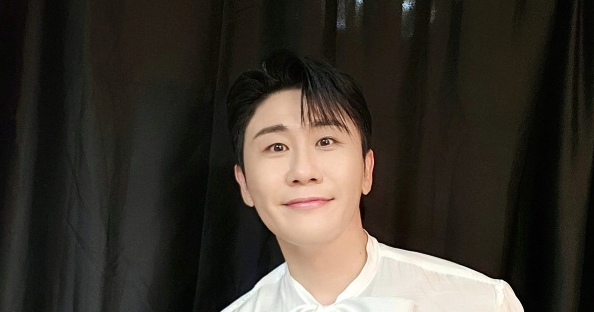 영탁이 하얀 리본 블라우스 차림으로 검은 커튼 앞에서 정면을 보며 은은하게 웃는 모습