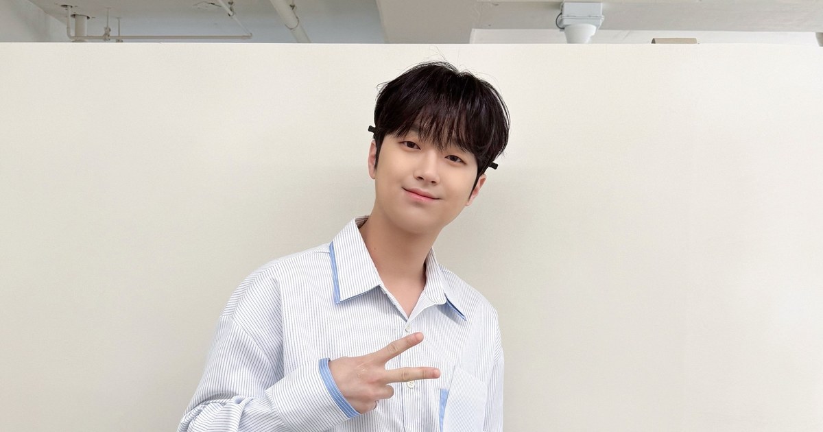 흰 벽 앞에서 줄무늬 셔츠 차림으로 브이를 그리며 웃는 이찬원