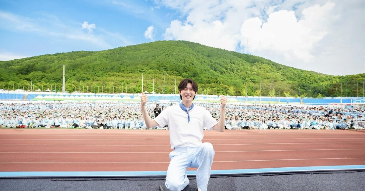하얀 티셔츠 차림으로 한쪽 무릎을 꿇고 두 엄지를 치켜든 김용빈, 뒤로 운동장 관중석과 푸른 산
