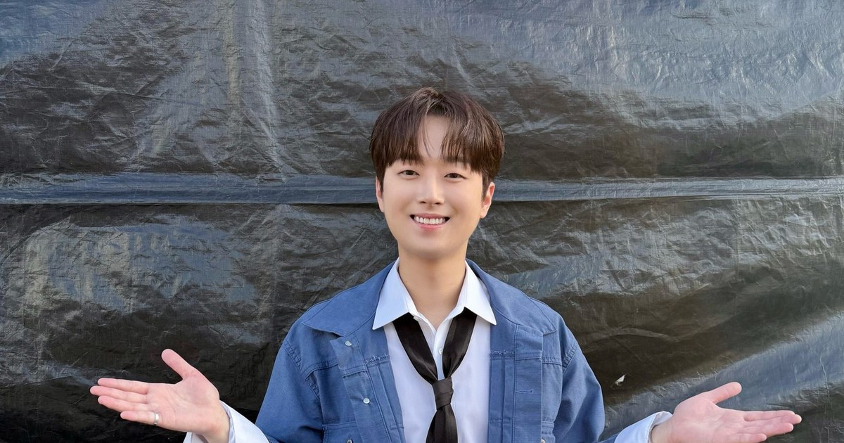 청색 데님 재킷에 넥타이 차림으로 두 팔을 벌리고 웃는 이찬원