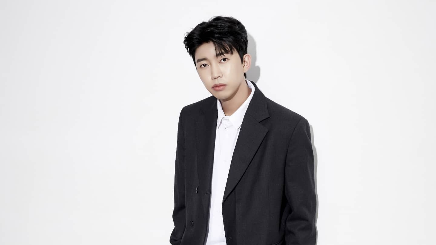 흰 배경 앞에서 검은 재킷과 흰 셔츠를 입고 정면을 바라보는 임영웅