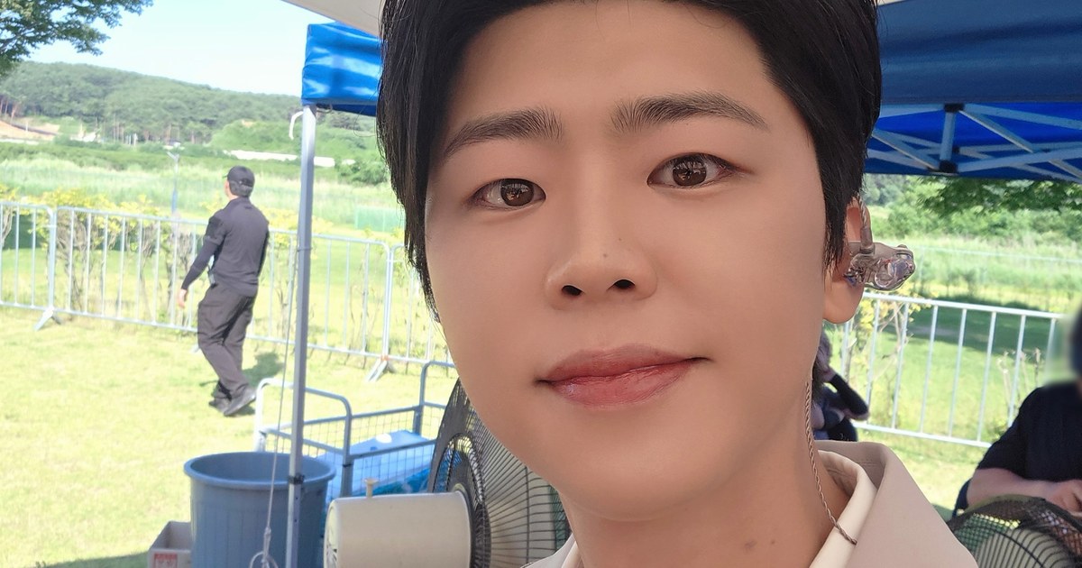 야외 천막 아래에서 베이지색 재킷을 입고 카메라를 향해 미소 짓는 박지현