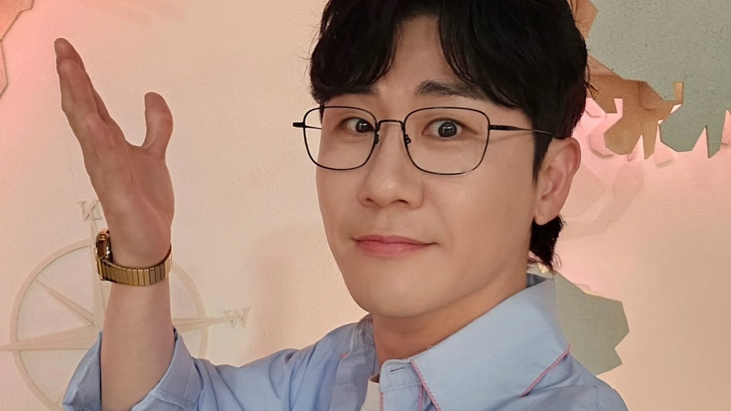 안경을 쓰고 정면을 바라보며 손을 들어 보이는 영탁